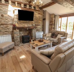 A living room with a fireplace and seating area at Tullythwaite Barn in Kendal