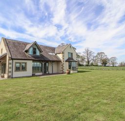 An exterior view of a house with grass and trees at Thimble Hill near Armathwaite
