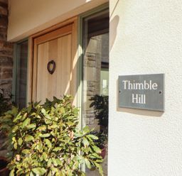 An entrance with a wooden door and a house number sign at Thimble Hill near Armathwaite