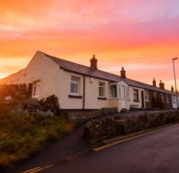 A house with a stone wall and road at 1 Sunny Brae in Embleton