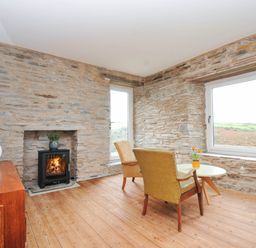 A living room with a fireplace and chairs at Boscabrea near Tintagel