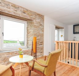 A living room featuring a table and chair with a plant at Boscabrea near Tintagel
