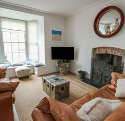 A living room with a television and a fireplace at Tri Raglan Mawr in Beaumaris