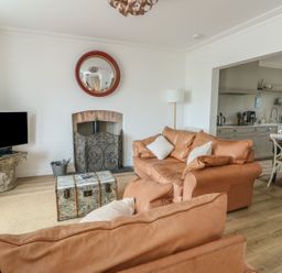 A living room with a television and sofa at Tri Raglan Mawr in Beaumaris