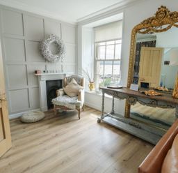 A living room with a chair and a mirror at Tri Raglan Mawr in Beaumaris