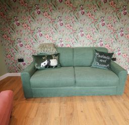 A living room with a green sofa and floral wallpaper at Unit 1 Ipswich