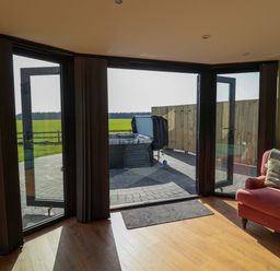 A living room with a hot tub visible outside at The Corn Silo in Ipswich