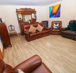 A living room with brown sofas and an ornate mirror at Ty-Gan Dderwen in Llangennech, Llanelli