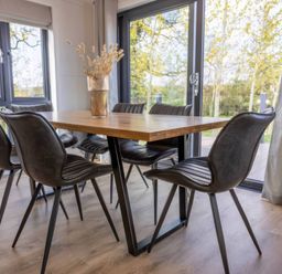 A dining table with chairs and a vase at Isca Lodge in Wombleton