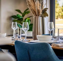A dining room table set with plates and glasses at Rye Lodge in Wombleton