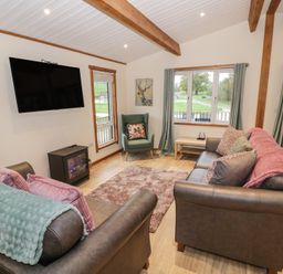 A living room with a sofa and a fireplace at Oak Lodge Admaston near Abbots Bromley