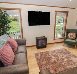 A living room with a television and sofa at Oak Lodge Admaston near Abbots Bromley