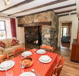 A dining room with a table and chairs near a fireplace at Ty Fferm in Newport