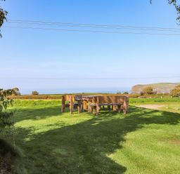 An outdoor seating area with a table and chairs overlooking the ocean at Ty Felin Newport