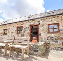 An outdoor area with wooden chairs and stone wall at Ty Felin Newport