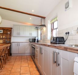 A kitchen with cabinets, dining table, and appliances at Ty Gwartheg in Newport