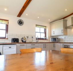 A kitchen with appliances and wooden table at Ty Cariad in Newport