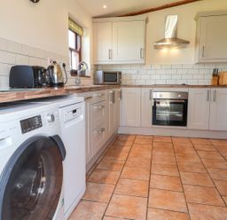 A kitchen with a washing machine and appliances at Ty Cariad in Newport
