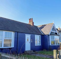 A house with blue exterior and a fence at Braeburn in Bamburgh