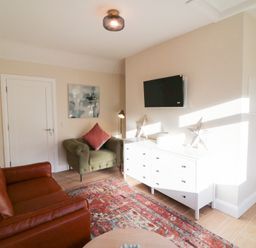 A living room with a sofa, armchair, and television at Duck Cottage