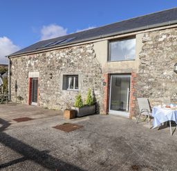An outdoor area with a stone building and patio furniture at Dairy Cottage Bullhornstone near South Brent
