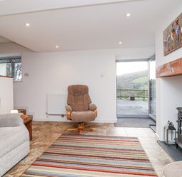 A living room with a sofa and a fireplace at Dairy Cottage in Bullhornstone near South Brent