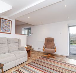 A snug with a sofa and armchair at Dairy Cottage in Bullhornstone near South Brent