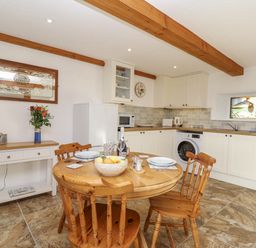 A kitchen with a round table and chairs at Swallow Cottage in Bullhornstone near South Brent