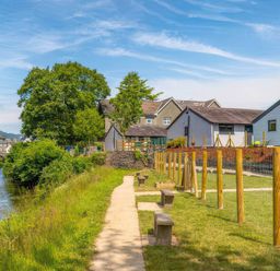 A path alongside a river with benches and buildings at Aspen Apartment in Llanrwst