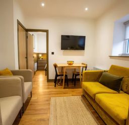A living room with a sofa, armchairs, table and television at Aspen Apartment in Llanrwst
