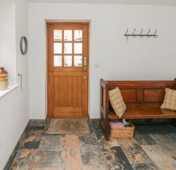 An entrance hall with a wooden bench and door at The Old Workshop 