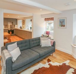 A living room with a sofa and adjoining kitchen at The Old Workshop in 