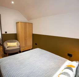A bedroom with a bed and wardrobe at White Willow Apartment in Llanrwst
