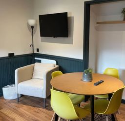 A dining room with a table and yellow chairs at Ash Cottages Llanrwst