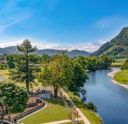 A view of a river and surrounding trees at Beech Cottages in Llanrwst