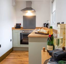 A kitchen with a bottle of champagne and bread at Beech Cottages in Llanrwst