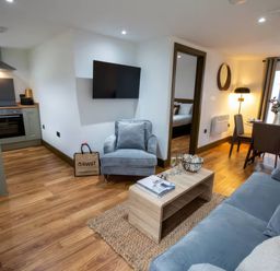 A living room with sofa and kitchen area at Beech Cottages Llanrwst