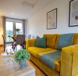 A living room with a yellow sofa and dining area at River View Cottage Llanrwst