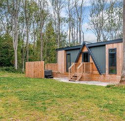 A house with a deck and hot tub surrounded by trees at Tennyson Spa in Louth