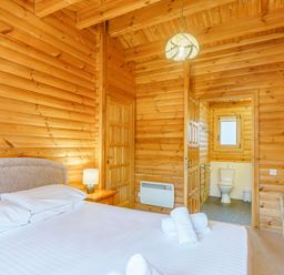 A bedroom with a bed and bathroom door at Maple Lodge in Louth
