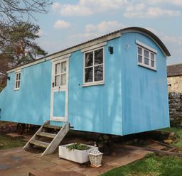 A blue shepherd's hut in a garden at Meadows in Hexham