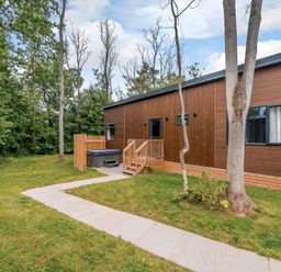A house with a hot tub and path surrounded by trees at Stamford Spa in Louth