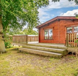 A wooden cabin with a deck and steps at Hazel Lodge in Louth