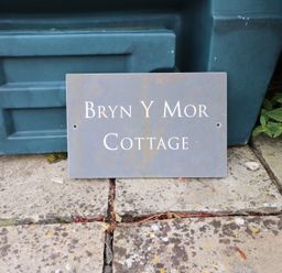 A sign with Bryn Y Mor Cottage on it near a garden in Mynytho near Llanbedrog