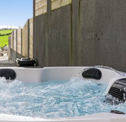 A hot tub with water and splashes near a fence at Heddfan in Carmarthen
