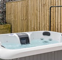 A hot tub with water surrounded by rocks and a wooden fence at Ty Uchel
