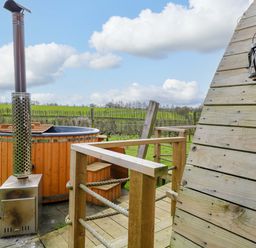 A hot tub with a chimney and wooden deck at Grape Escape near Halesworth