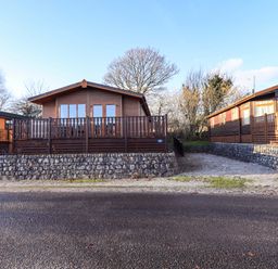 Log cabin with wooden deck and stone wall at Kingfisher Lodge