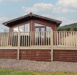 A wooden cabin with decking and railings at Monach 1