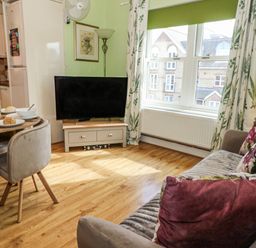 A living room with a tv and dining table at Rodwell Holt in Weymouth
